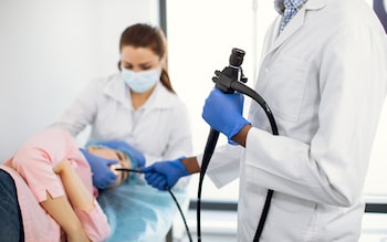 doctor in white coat and rubber gloves standing with a modern endoscope