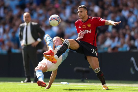 Manchester City's Erling Haaland challenges for the ball with Manchester United's Diogo Dalot 