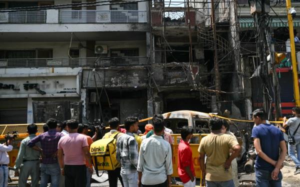 Men gather near the remains of an accident site a day after fire blazed through a children's hospital in New Delhi on May 26, 2024. Six newborn babies have died after a fire tore through a children's hospital in the Indian capital, with people charging into the flames to rescue the infants, police said on May 26. (Photo by Arun SANKAR / AFP)