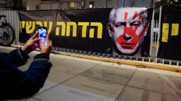 A person takes a picture of a banner, during a protest against Israeli Prime Minister Benjamin Netanyahu's government in Tel Aviv, Israel, January 20, 2024. REUTERS/Alexandre Meneghini</p>

<p>　　