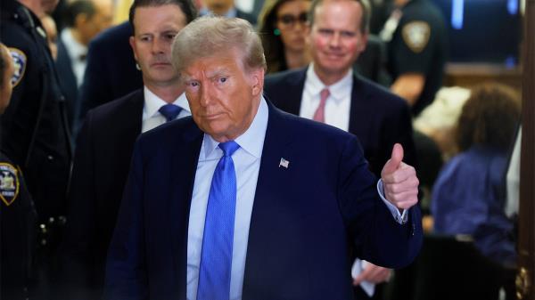 Do<em></em>nald Trump in blue tie, dark coat giving thumbs up