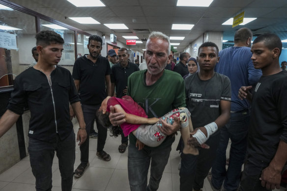 A Palestinian brings a child wounded in the Israeli bombardment of the Gaza Strip into a hospital in Deir al Ballah.