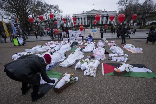 Palestinian supporters calling for an immediate ceasefire, stage a mock funeral with dolls and people wrapped in white cloth smeared with red pain to resemble Palestinian victims of the Israel-Hamas war, in front of the White House in Washington, Saturday, Dec. 2, 2023. (AP Photo/Manuel Balce Ceneta)