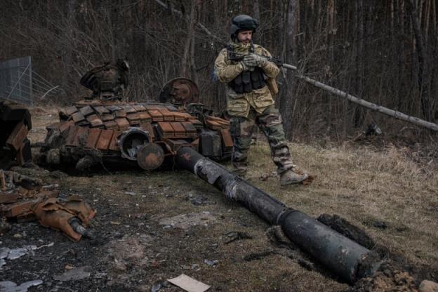 A Ukrainian soldier walks past remnants of a destroyed Russian tank in Stoyanka, Ukraine, on March 27, 2022.