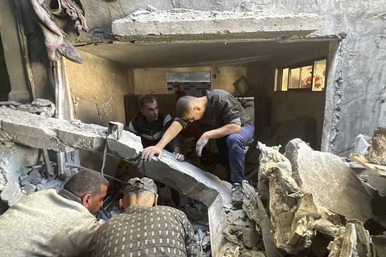 People look through the rubble of a home destroyed by an Israeli airstrike on Dec. 6, 2023, in Nuseirat refugee camp in the Gaza Strip. Four-year-old Omar Abu Kawaik was pulled alive from the rubble and brought out of Gaza then flown to the United States, wher<em></em>e he received treatment including a prosthetic arm. (Courtesy of Maha Abu Kuwaik via AP)