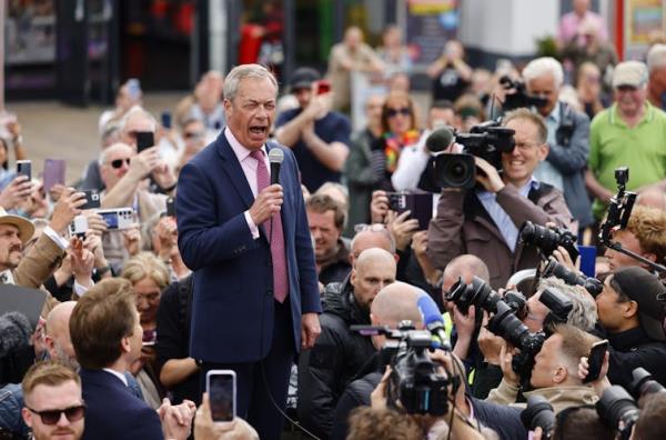 Nigel Farage shouting into a microphone, surrounded by press.