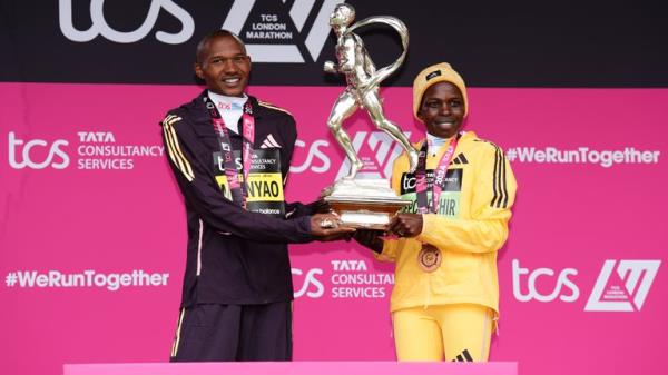 Alexander Mutiso Munyao and Peres Jepchirchir with their trophies and medals on the podium after winning the men's and women's elite races during the TCS Lo<em></em>ndon Marathon. Pic: PA 