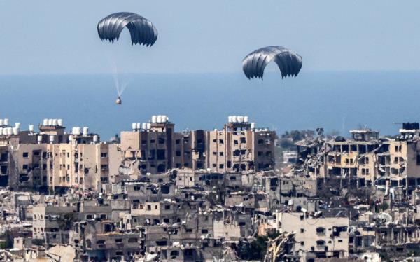 This picture taken from Israel's southern border with the Gaza Strip shows parachutes of humanitarian aid dropping over the besieged Palestinian territory on March 26, 2024, amid the o<em></em>ngoing co<em></em>nflict between Israel and the militant group Hamas. Seven people have drowned in the Mediterranean trying to reach aid airdropped into Gaza, the Hamas-run territory's health ministry said on March 26. Six people were also injured in the previous day's airdrop, the ministry said. Hamas said a total of 18 people have now been killed in drownings or stampedes since aid airdrops to the starving north of the besieged territory began. (Photo by JACK GUEZ / AFP)