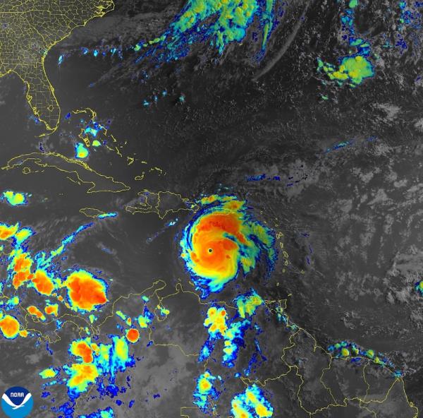 Satellite view of large hurricane in colors of red, orange, blue, and green in the Caribbean.