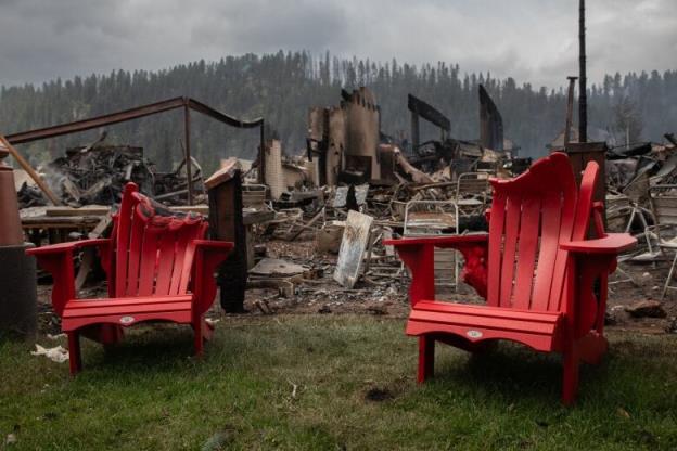 Two melted red chairs in front of a destroyed building.