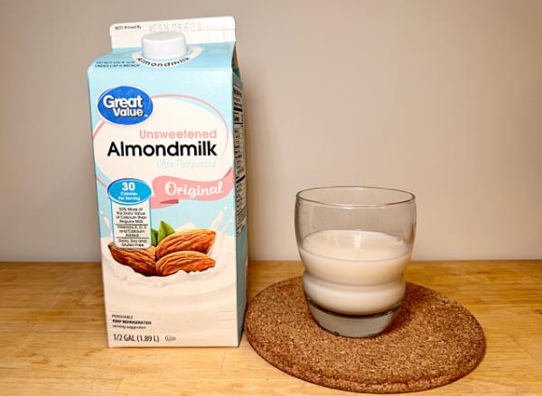 a co<em></em>ntainer of great value almond milk next to a glass of it 