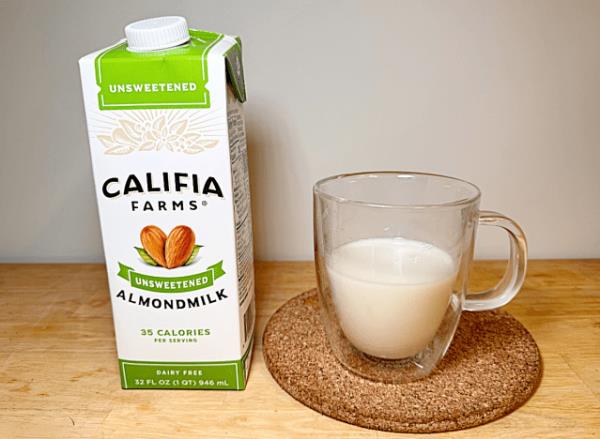 a co<em></em>ntainer of califia almond milk next to a glass of almond milk 