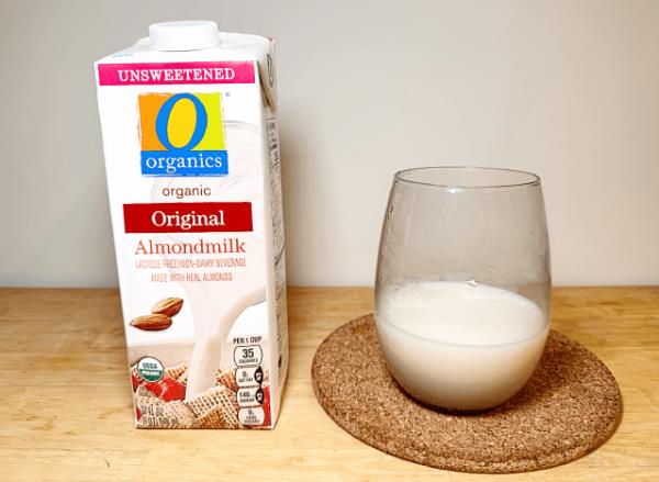 O organics almond milk co<em></em>ntainer next to a glass of it 