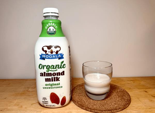 mooala almond milk co<em></em>ntainer next to a glass of it 