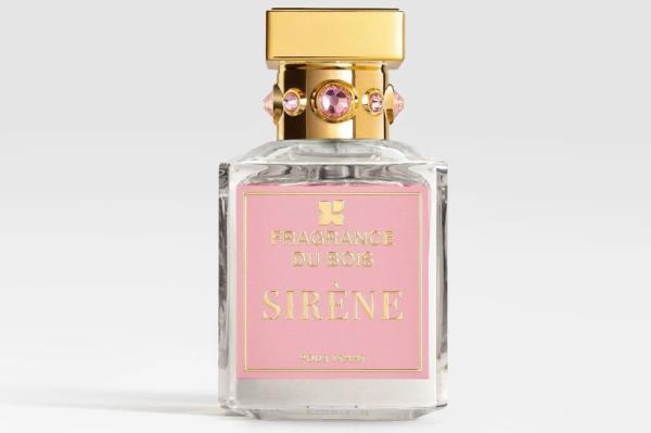 A bottle of perfume with a gold cap and pink label