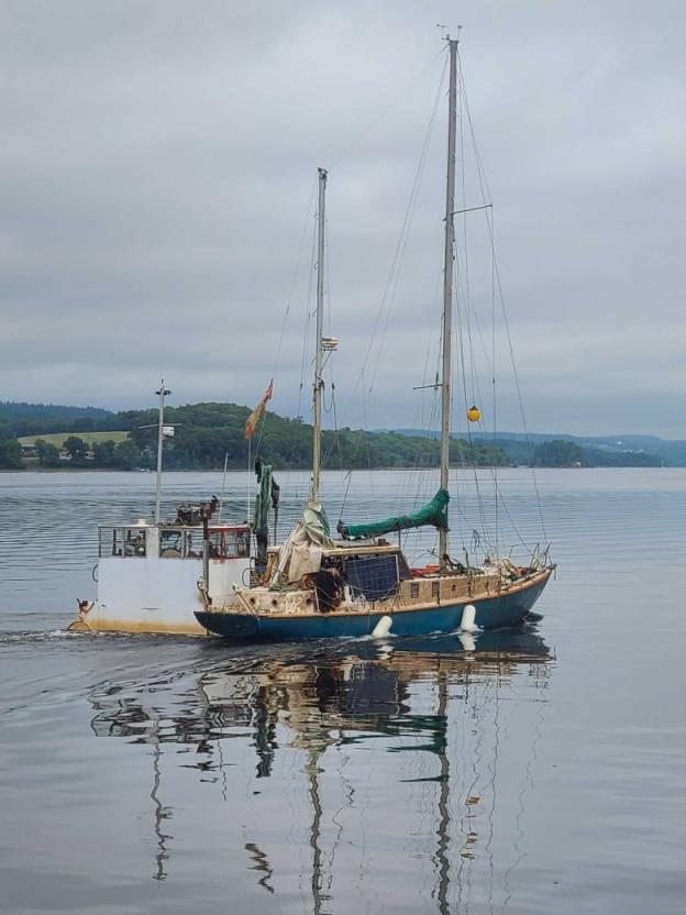 A barge hauling an old sailboat.