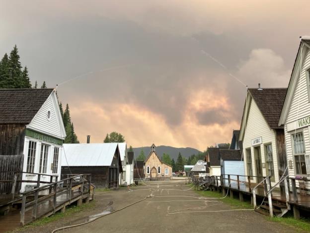 Hoses spray water on houses as smoky co<em></em>nditions linger.