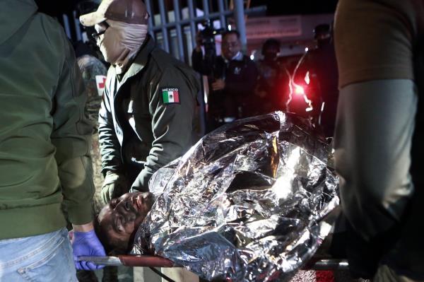 The charred bodies of migrants, wrapped in foil-like blankets, were removed from the facility Mo<em></em>nday night.