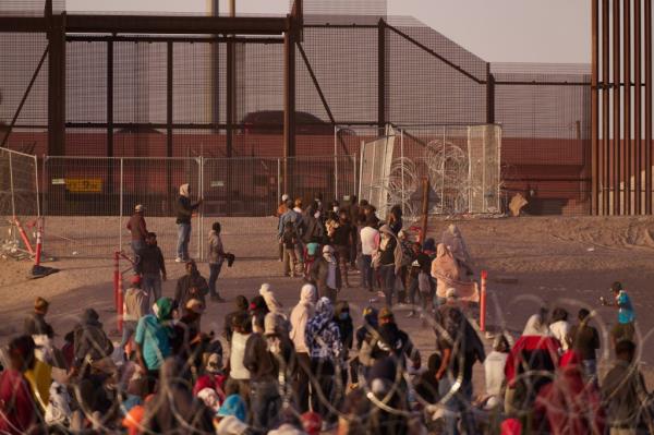 A migrant gestures to Texas Natio<em></em>nal Guards standing behind razor wire on the bank of the Rio Grande river,