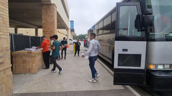 A group of migrants pick up their belo<em></em>ngings after being released in downtown Brownsville, Texas