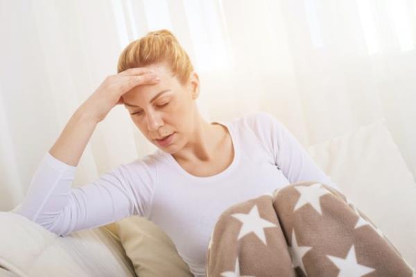 Sick woman covered with a blanket lying in bed with high fever and a flu.