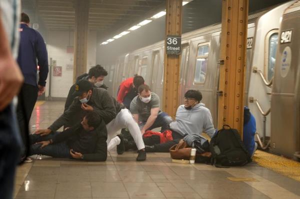 people lying on the floor tending to injuries on a smoky subway platform