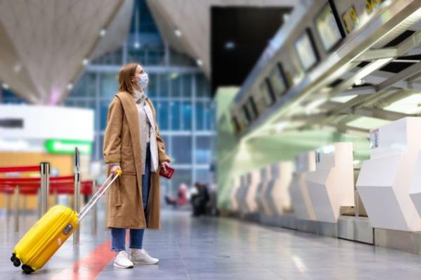 Woman with luggage stands at almost empty check-in counters at the airport terminal due to coro<em></em>navirus pandemic/Covid-19 outbreak travel restrictions.