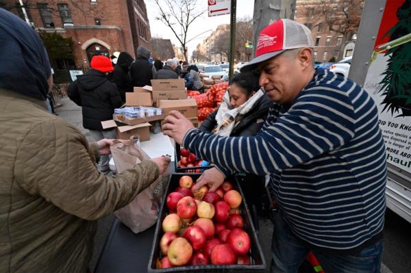 Newly arrived migrant Luis Moreira (42, of Ecuador) helps out to distribute food bank to a needy.