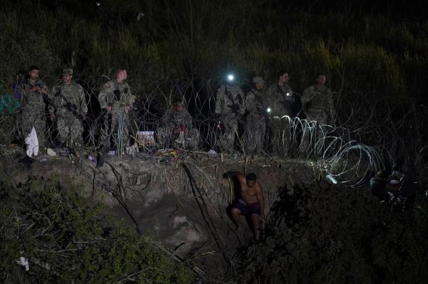 Texas Natio<em></em>nal Guard members stand along a stretch of razor wire as migrants try to cross into the United States on the banks of the Rio Grande, as seen from Matamoros, Mexico on May 11, 2023.