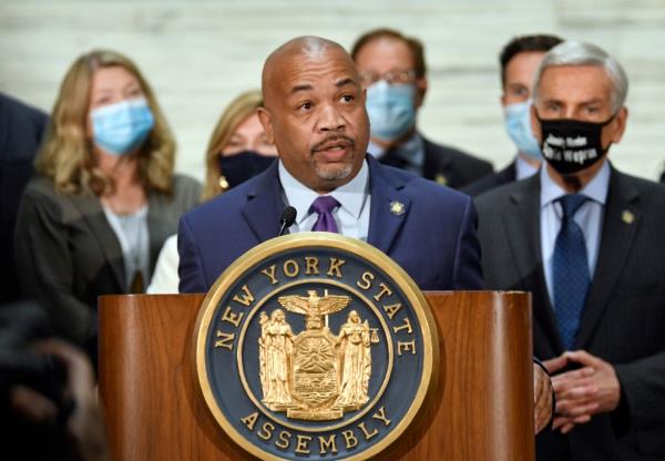 Carl Heastie speaking at a podium with blurry assembly members in the background