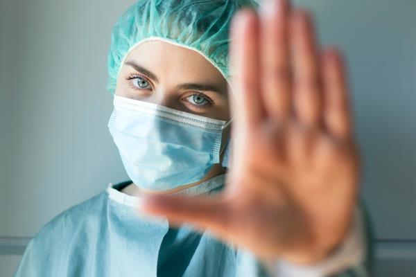 Caucasian young female doctor looking in camera while making stop sign with hand.