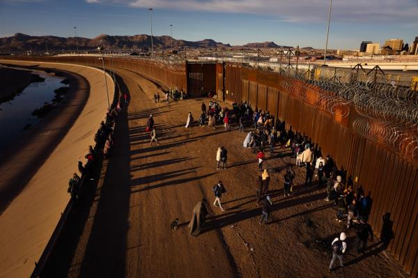 A group of migrants gathered at a border wall after crossing into El Paso, Texas on December 31, 2022.