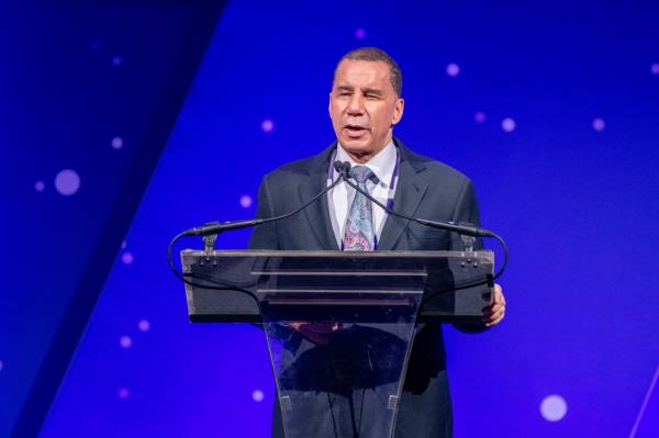 avid Paterson in a suit speaking at a podium with a deep blue background