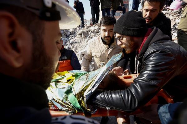 A rescuer covers Aisha with a blanket.