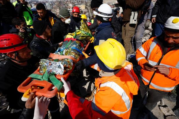 Aisha is lifted on a stretcher amid the rubble.