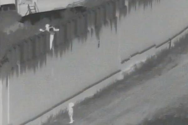 The smuggler attempts to hop down the barrier to aid the 4-year-old child from the top of a roughly 30-foot US-Mexican border wall. 