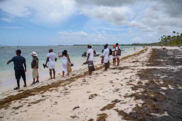 Tourists walk along the shore of the beach partially covered by sargassum at Bibijagua Beach in Punta Cana, Dominican Republic.