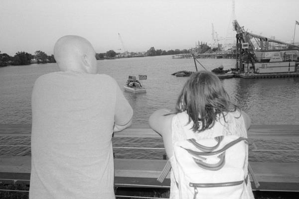 people look out over the water wher<em></em>e a boat with a flag is floating.