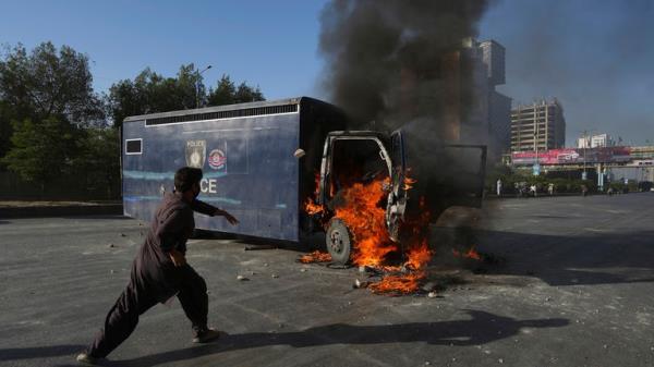 A man runs past a burning prison van set on fire by angry supporters of Pakistan's former Prime Minister Imran Khan during a protest against the arrest of their leader, in Karachi, Pakistan</p>

<p>　　Pic:AP