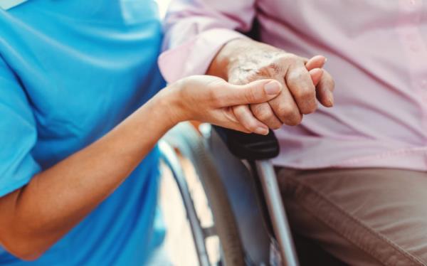 Nurse co<em></em>nsoling a senior woman in the nursing home holding her hand in the nursing home