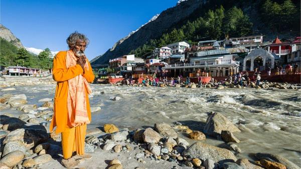 GANGOTRI, UTTARAKHAND, INDIA - 2015/05/27: The very im<em></em>portant pilgrimage place for Hindus and Buddhists is located at the young river Ganges and part of the Chota Char Dham, a devotee is praying at the waterfront