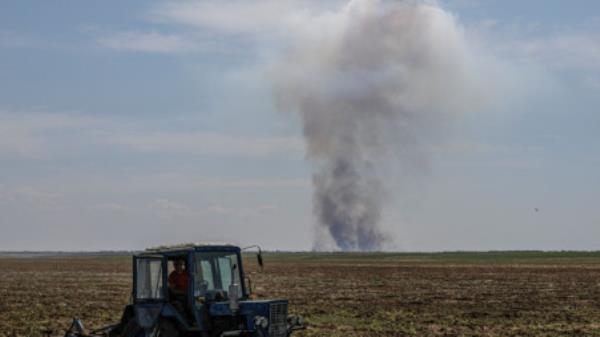 An agricultural worker operates a tractor as smoke rises in the distance after a military strike, in Kherson region, Ukraine, June 20, 2023. REUTERS/Andrii Dubchak</p>

<p>　　