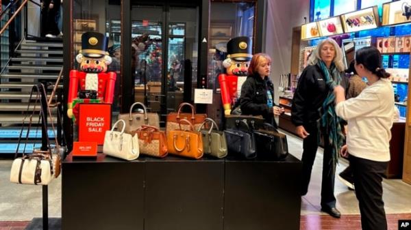 Shoppers pause near a display of handbags at a Coach store in New York on Nov. 19, 2023.