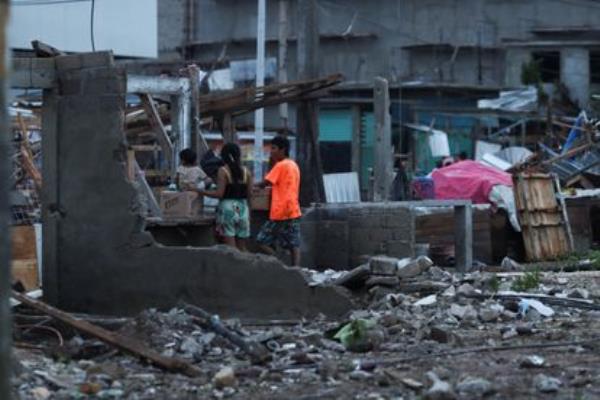 People stand near street stalls damaged by Hurricane Otis in Acapulco, in the Mexican State of Guerrero, October 25, 2023. 