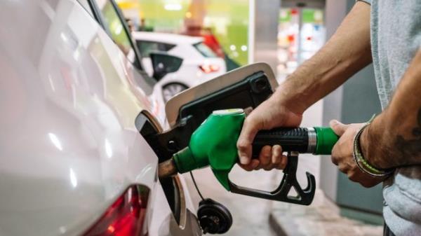 Unrecognizable male putting fuel dispenser in tank while refueling vehicle on self service gas station. High quality photo