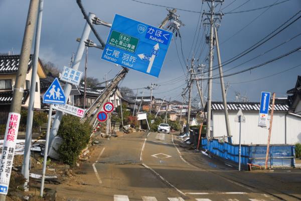 Crooked signs hang over a road damaged in the January 1 earthquake in Nishiaraya