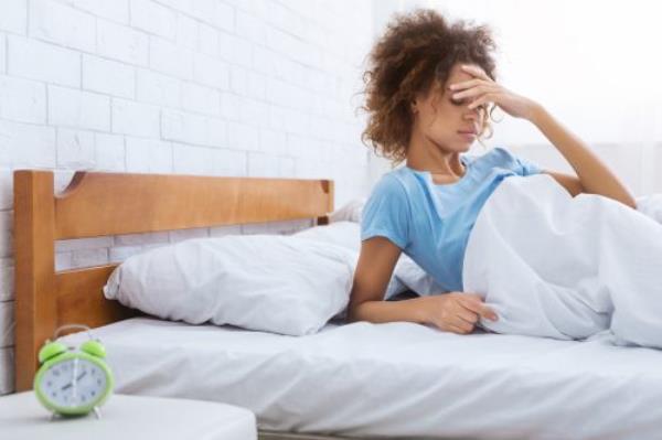 Woman touching forehead, havin<em></em>g headache in the morning, sitting on bed