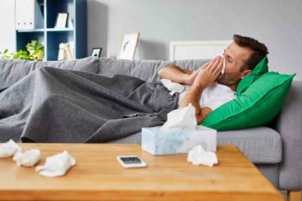 sick man blowing his nose on the couch