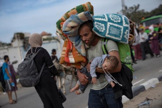 A man loaded with blankets carrying a baby. 