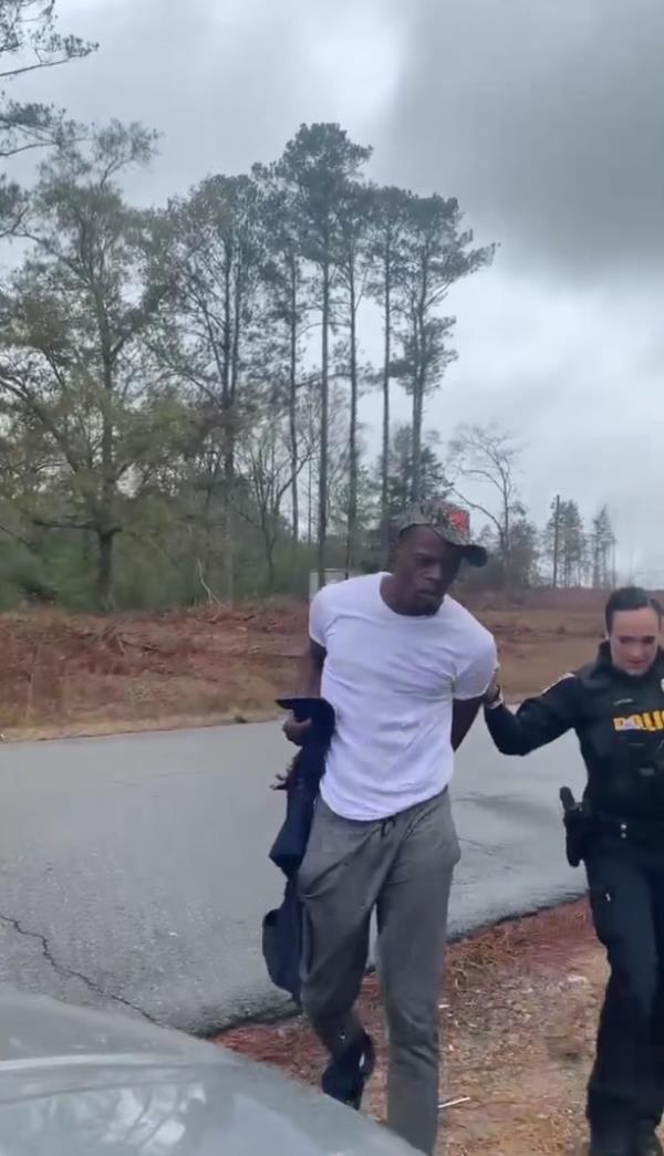 White cop leading Black man to her car